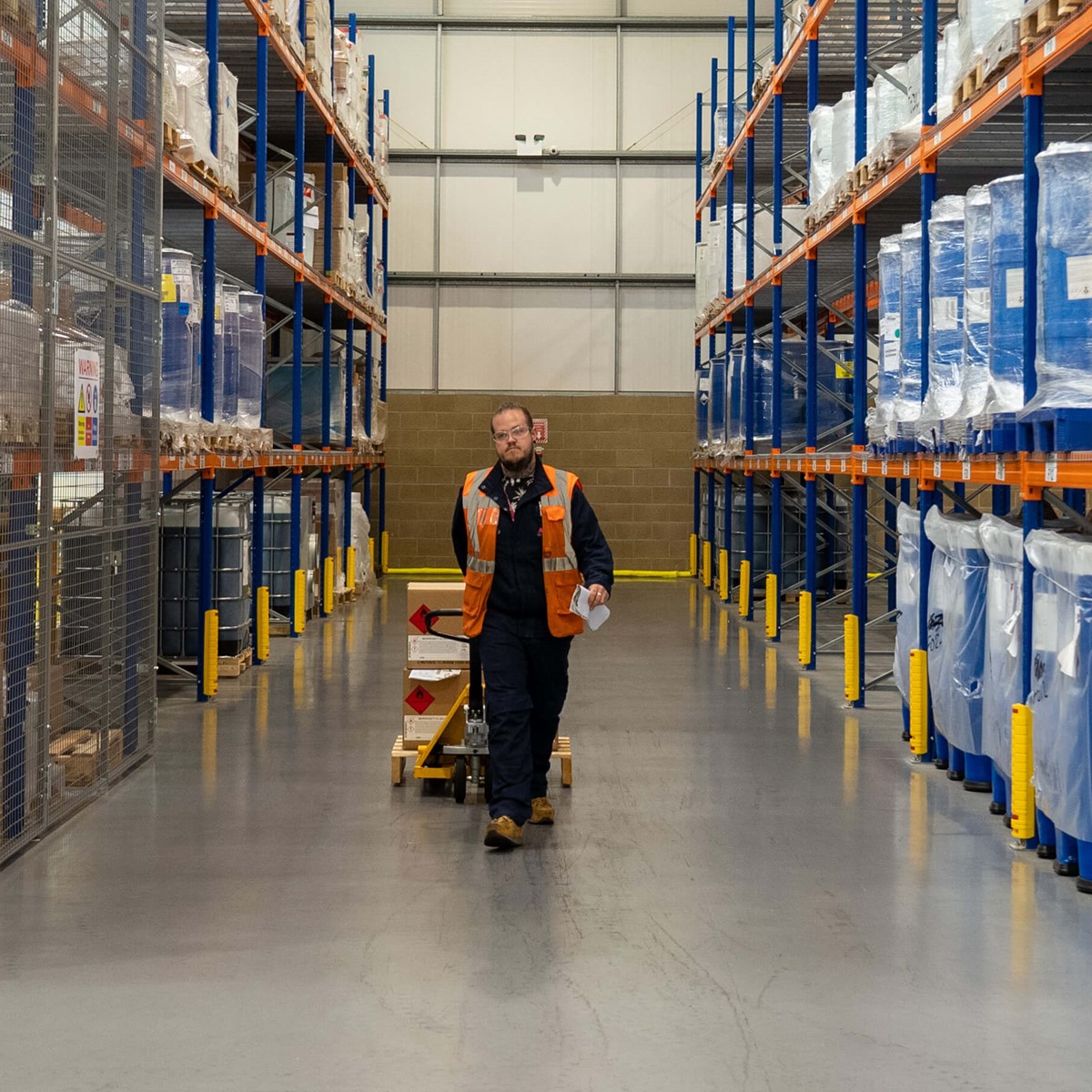 Man pulling a pallet of cardboard boxes in a warehouse